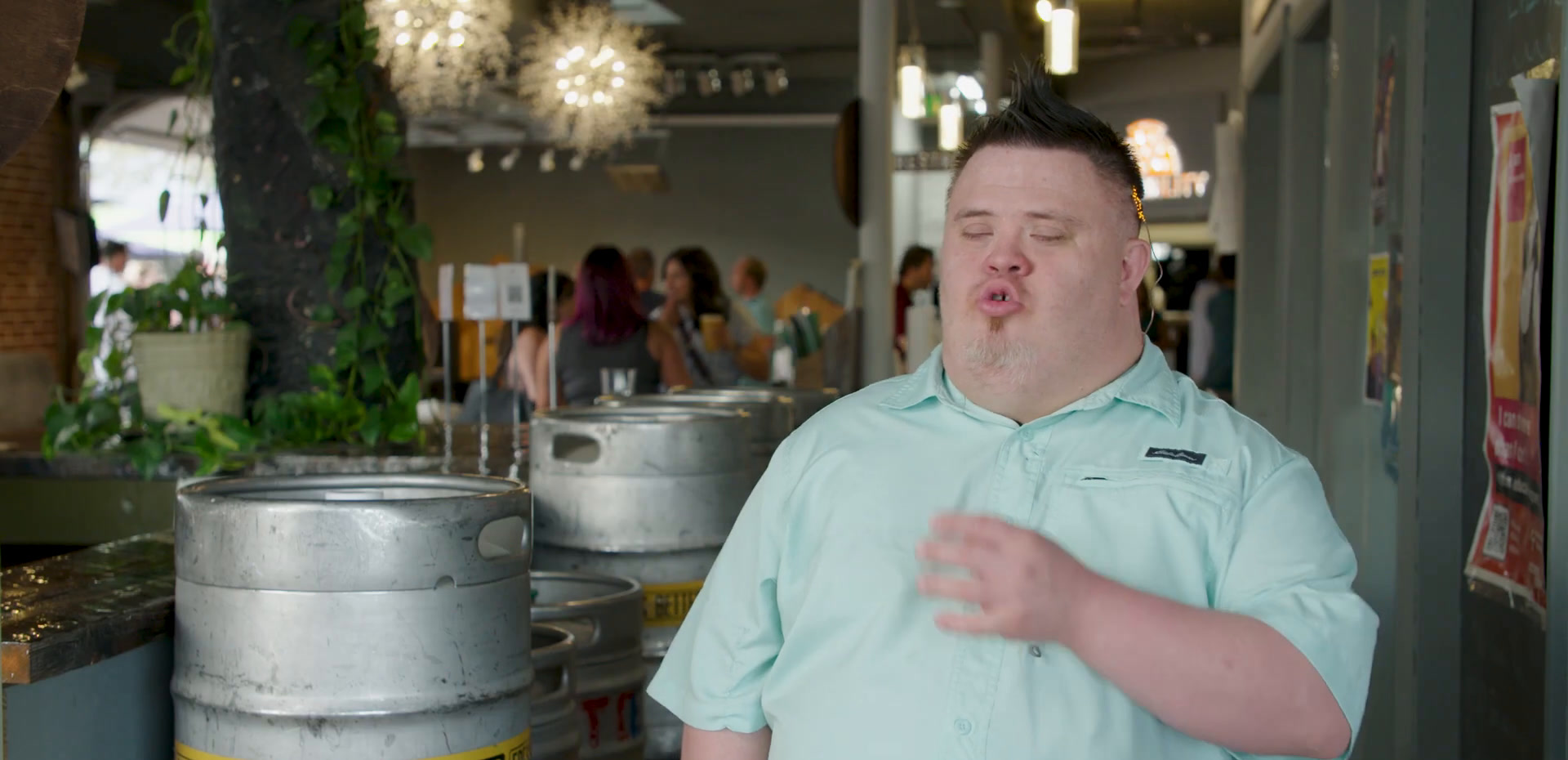 José in a mint green polo shirt beside the beer kegs, animatedly chatting with someone off camera.
